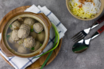 Bakso Sapi or Meatball traditional popular street food in Indonesia, served with clear soup, and noodles. Grey wooden background. Selective focus, copy space. 