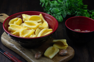 Buah Nangka or Jackfruit, one of tropical fruits popular in Indonesia. Cut into  half on red bowl and the seeds at behind. Dark wooden background. 
