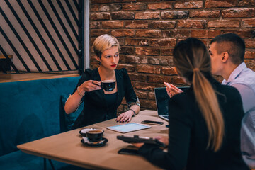Young blonde female consultant drinking coffee during her business meeting in a cafeteria