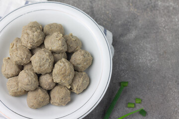 Bakso Sapi or Meatball traditional popular street food in Indonesia, served with clear soup, and noodles. Grey wooden background. Selective focus, copy space. 