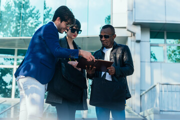 Well-dressed young male discussing business project documents with his multi-ethnic colleagues outside the office