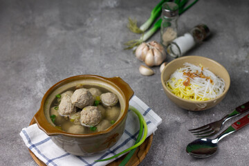 Bakso Sapi or Meatball traditional popular street food in Indonesia, served with clear soup, and noodles. Grey wooden background. Selective focus, copy space. 
