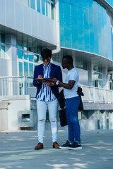 Two male colleagues reviewing their documents outside after work.