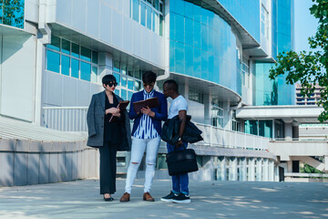 Businessman showing documents to his multi-ethnic co-workers in front of their big modern office building