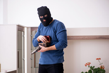 Male robber stealing valuable things from the house