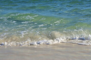 On the beach - ocean water, yellow sand, white foam on the water, close-up