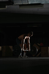 Fototapeta na wymiar Silhouette of a fit strong shirtless athlete doing squats. Weight lifting workout concept.