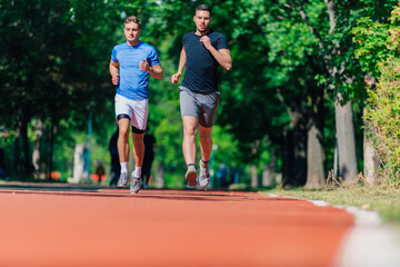 Obraz premium Two healthy young men running in the park on a sunny day..