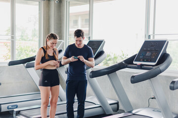 Fototapeta na wymiar Couples exercise at the gym. Couple having fun playing with smartphones Near the exercise machine