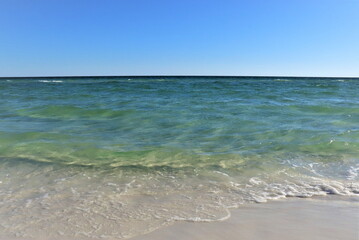 Fototapeta na wymiar View of the Gulf Coast from the shore, green ocean, wave and wet sand, blue sky