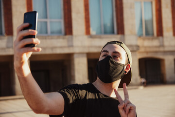 young man with black mask, taking a selfie with smartphone, social media, copy space, new normal, communications, millennial