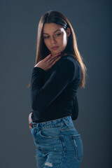 Beautiful young female model in jeans on dark background