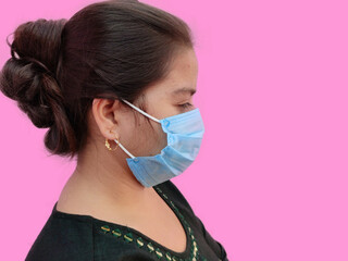 Side view of young indian woman face wearing medical face mask on white background. Protect your health. Coronavirus concept