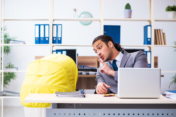 Young male employee looking after newborn at workplace