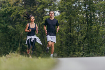 Obraz premium Young fit couple atheltes running on running road in a forest.