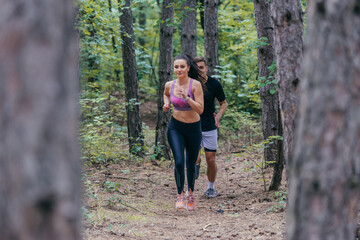 Fit male and female athletes running in nature. Nature and sports concept.