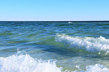 Seascape, green ocean waters, small waves, blue sky above the horizon