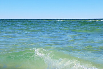 Seascape, green ocean waters, small waves, blue sky above the horizon