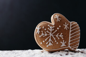 Christmas and New Year traditional attribute, festive sweets for kids, celebration mood. Homemade gingerbread cookie on dark background
