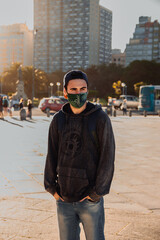 young caucasian man with chinstrap mask in the middle of the square with sunlight, new normal campaign, travel, tourism opening, social media, copy space