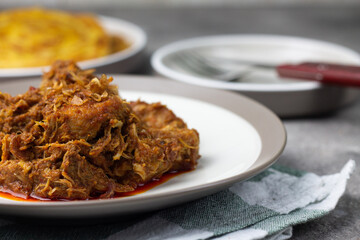 Ayam Kari or chicken curry, Indonesian traditional food served on ceramic plate, very popular at hari raya celebration food with roti canai, lontong, buras and ketupat. Grey wooden background.