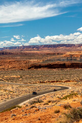 Cars roll down the desert through paved highway on a land that appears like from another planet, Page, AZ