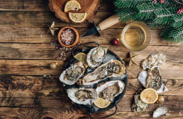 Oysters with lemon on a vintage dish on a rustic wooden background with a festive decor. Christmas...
