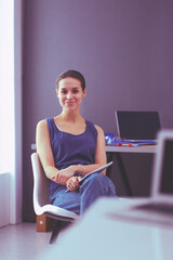 Young woman sitting at the desk with instruments, plan and laptop.
