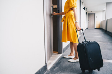 Cropped shot view of tourist woman pulling her luggage to her hotel room after check-in. Conceptual of travel and vacation. - obrazy, fototapety, plakaty