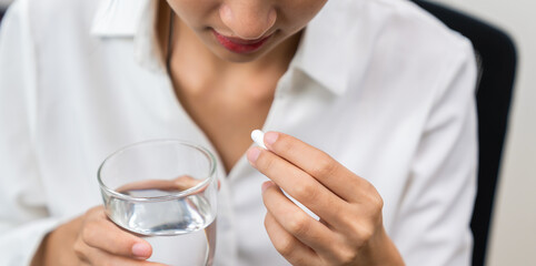 Woman taking medicine and holding a glass of water in hand, Because there is an illness.