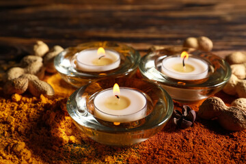 Burning candles with spices and nuts for celebration of Divaly on wooden background