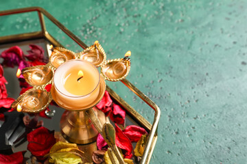 Tray with diya lamp for celebration of Divaly on color background