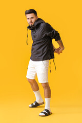 Fashionable young man on color background