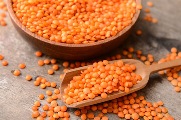 Bowl and scoop with raw lentils on wooden table, closeup