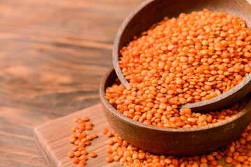 Bowls with raw lentils on wooden table, closeup