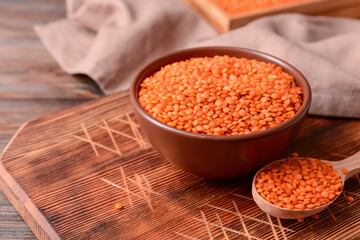 Bowl and spoon with raw lentils on table