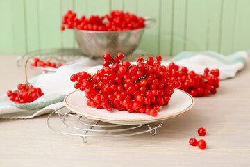 Plate with fresh viburnum berries on table