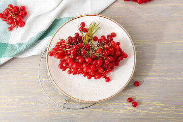 Plate with fresh viburnum berries on table