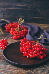Plate with fresh viburnum berries on table