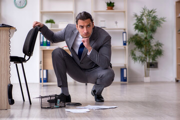 Young male employee and mousetrap in the office