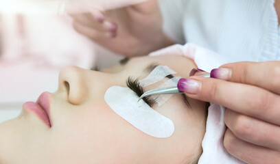 Naklejka premium Eyelash Extension Procedure. Woman Eye with Long Eyelashes. Beautiful young girl eyelash extensions.
