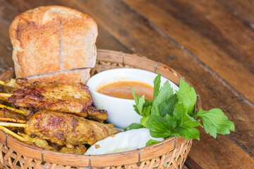 Pork satay with peanut sauce in basket.