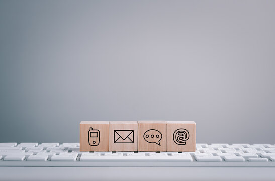 Website page contact us or e-mail marketing concept, Customer support hotline Contact us people connection. cube wood with the email, call phone, address, Chat message icons. on keyboard computer,