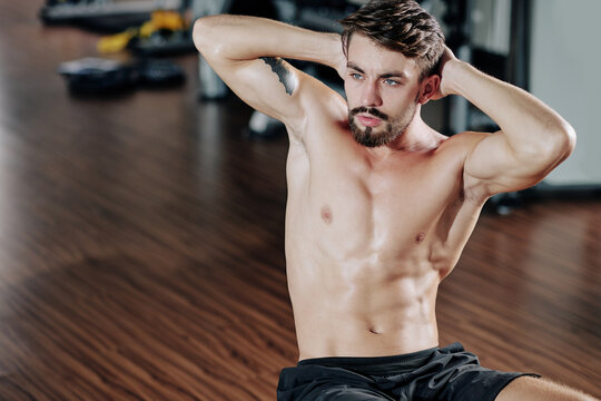Shirtless attractive fit young man doing crunches in gym