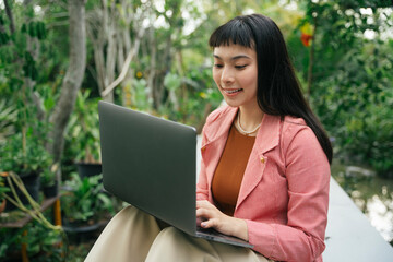 Asian woman in formal shirt working on laptop computer.