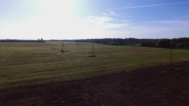 Power Supply Pole Lines In Agricultural Fields On a Sunny Day. Aerial Flying Forward Footage.