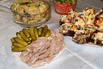 Festive table. Boiled pork tongue with pickles and spices, salted mushrooms seasoned with herbs, stuffed eggplant.