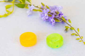 cough sore throat pastille colorful pills with purple flower arrangement flat lay style on background white