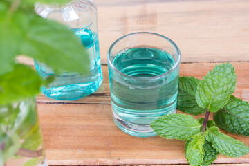 mouthwash from herbal peppermint in glass health care for oral cavity with mint leaf on background wooden