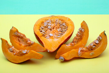 Pieces of cut Hokkaido pumpkin on colored background